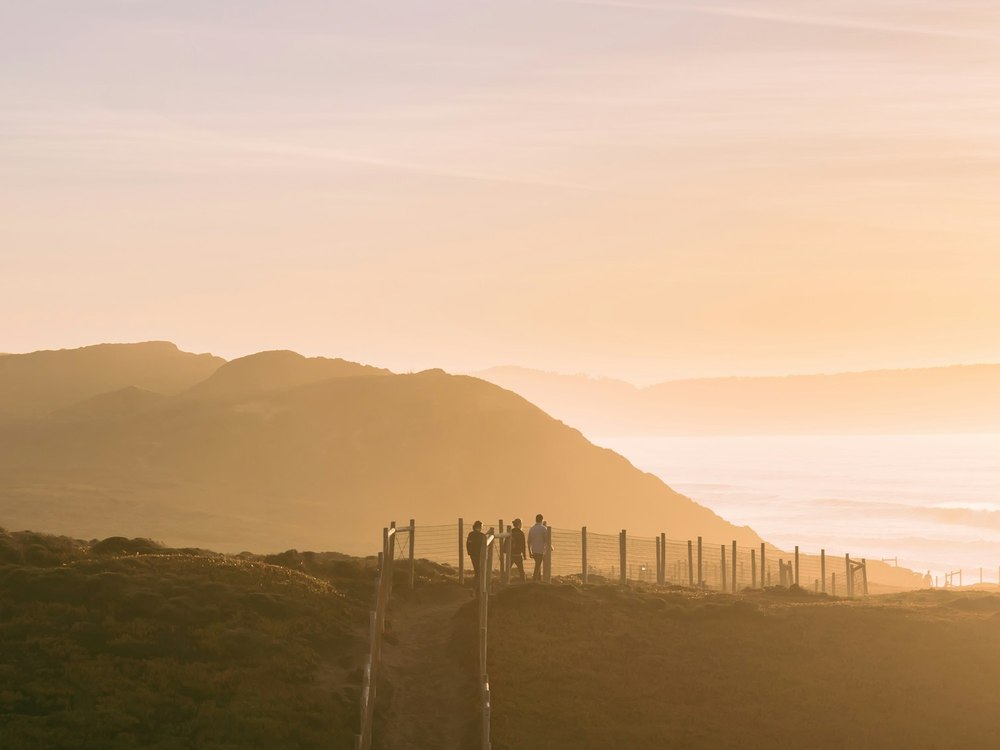 Hikers on a ridgeline above the coast at sunrise